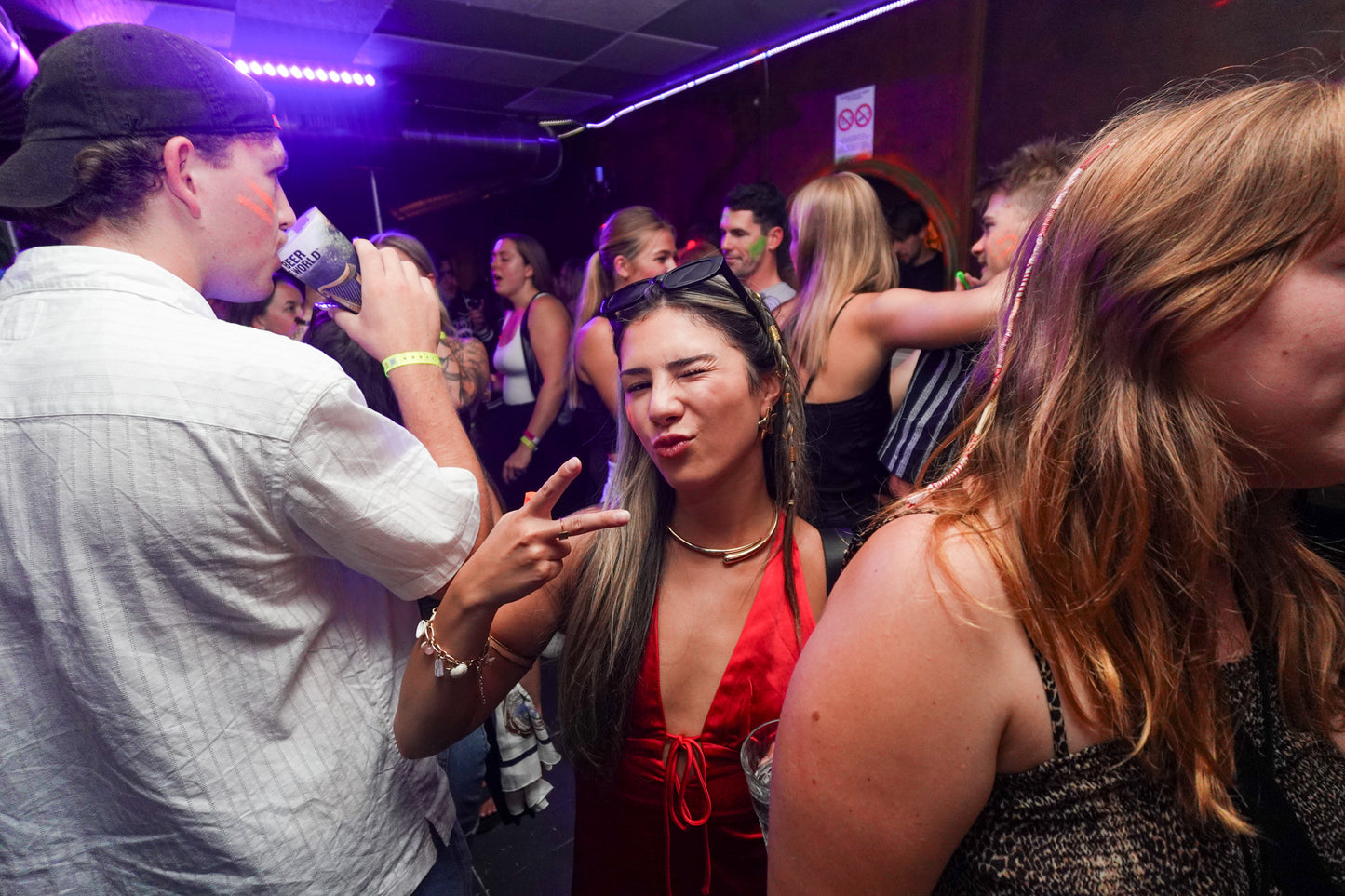 Young woman posing at a party during the Beer&Dash pub crawl in Nice, France, with vibrant club atmosphere.