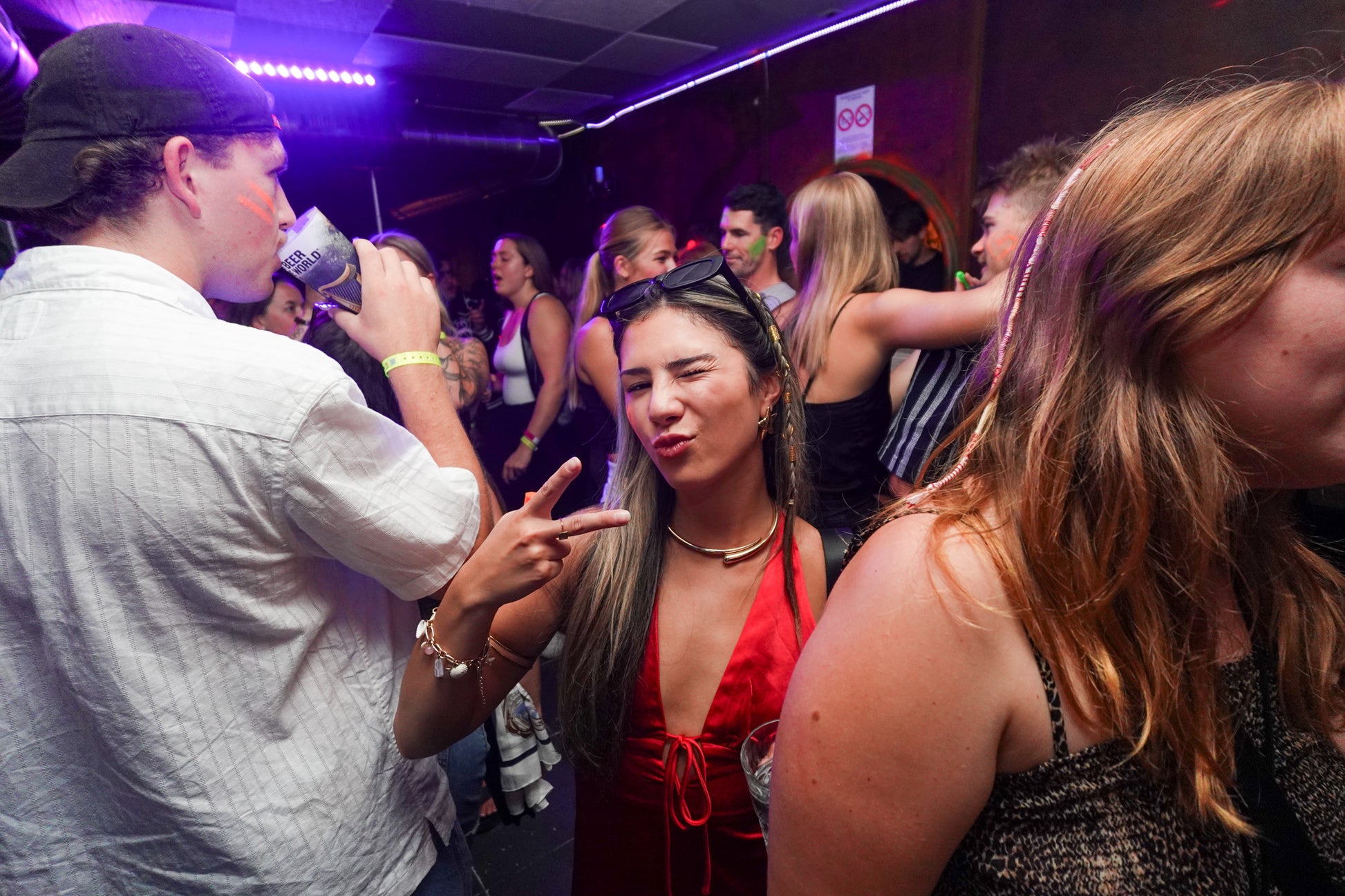 Young woman posing at a party during the Beer&Dash pub crawl in Nice, France, with vibrant club atmosphere.