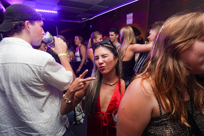 Young woman posing at a party during the Beer&Dash pub crawl in Nice, France, with vibrant club atmosphere.